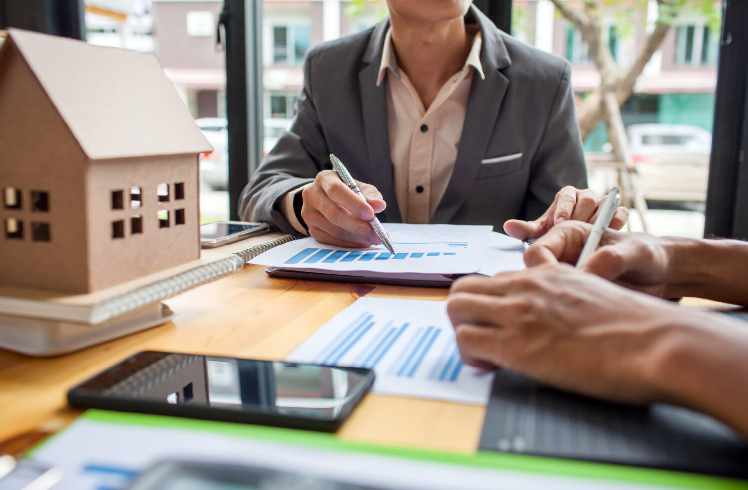 Business meeting tiny wooden home and documents on table