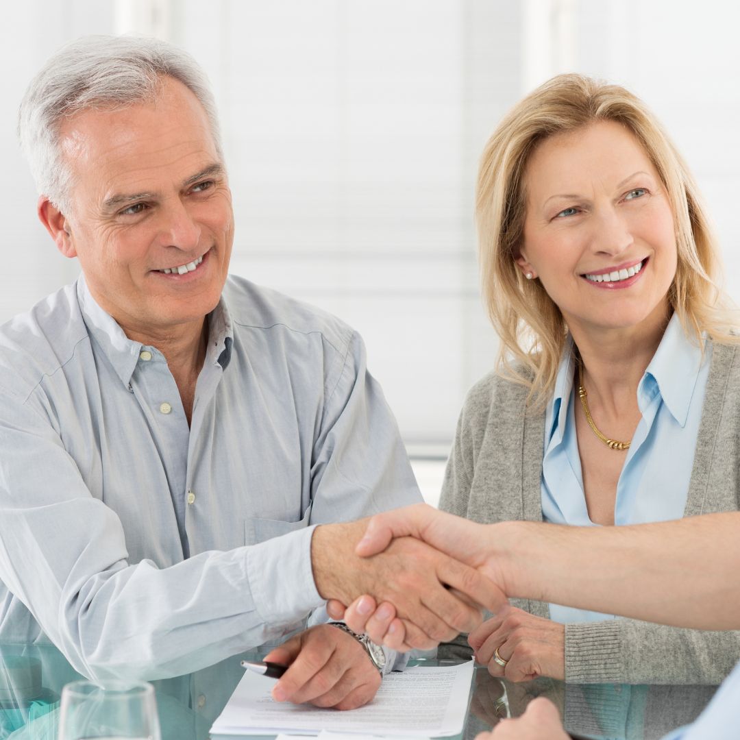 elderly couple shaking attorney's hand