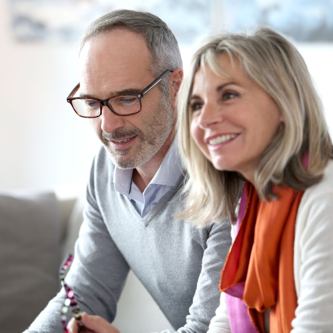 elderly couple sitting and smiling at attorney offsecreen