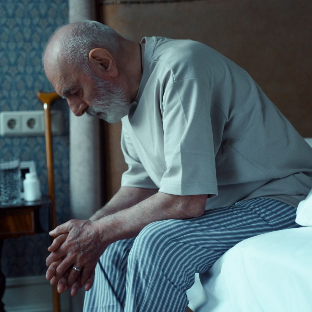 older man sitting on the edge of the bed