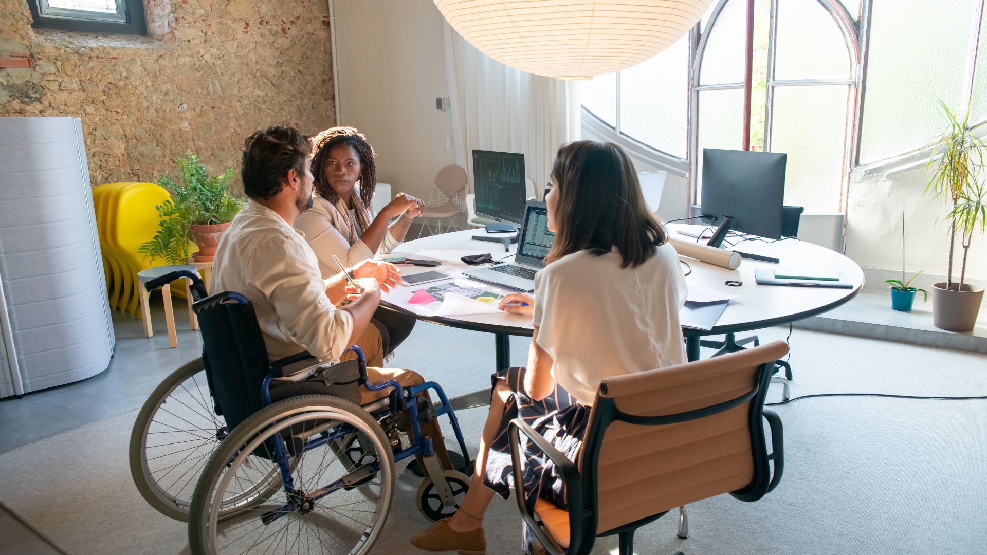 person in wheelchair meeting with two woman