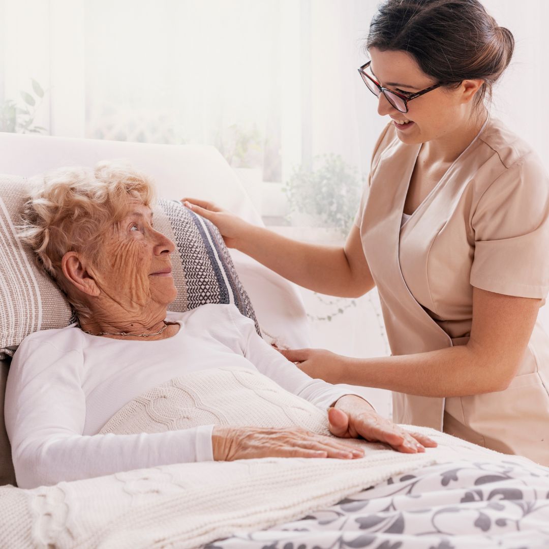 older woman in best speaking with nurse