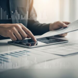 Hands analyzing financial data on a tablet and spreadsheet.