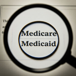 A magnifying glass focused on the words 'Medicare' and 'Medicaid' on a document.