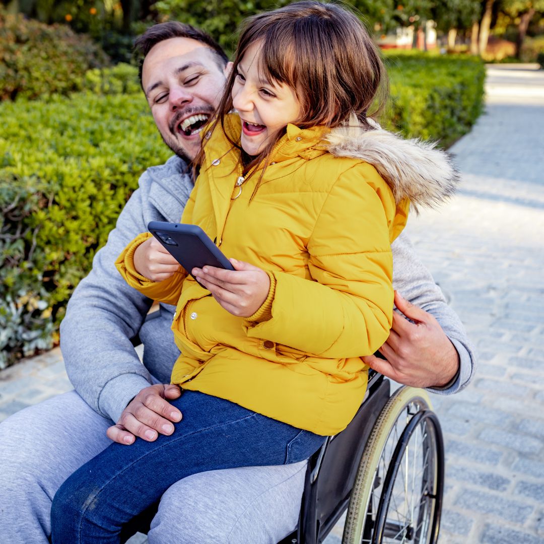 father in wheelchair holding daughter in lap